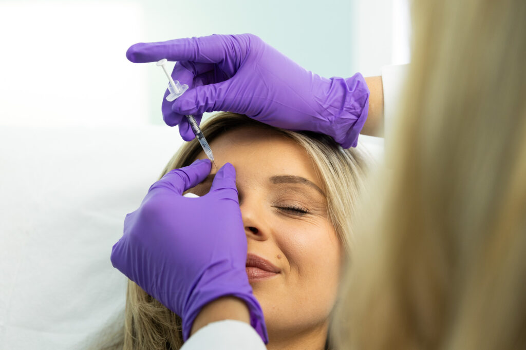 A woman smiles as a provider administers Botox for migraines in St. Petersburg.