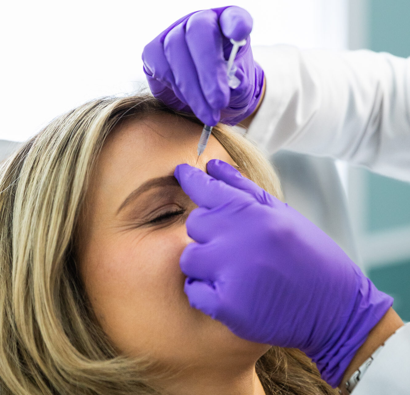 A woman shuts her eyes as she receives Botox for migraines in St. Petersburg.