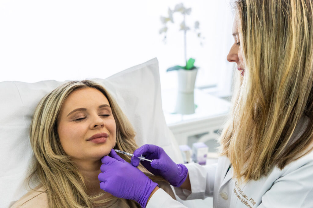 A woman reclines and smiles as a provider injects masseter Botox in St. Petersburg.