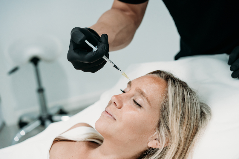 A young woman is lying down and receiving Botox injections after searching "Botox near me" and discovering Hermann Aesthetics